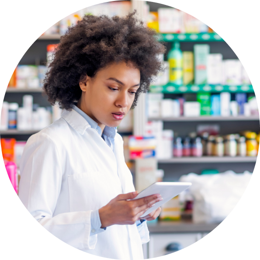 A female clinician in a pharmacy looks at a tablet